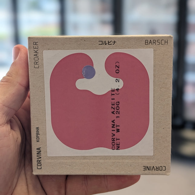 Hand holding a small cardboard box with fish illustration and text