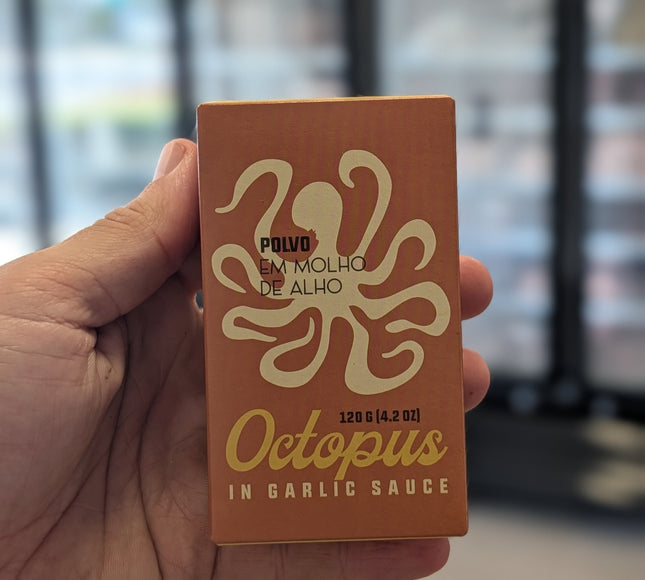 Hand holding a box of 'Octopus in Garlic Sauce' with an octopus logo.