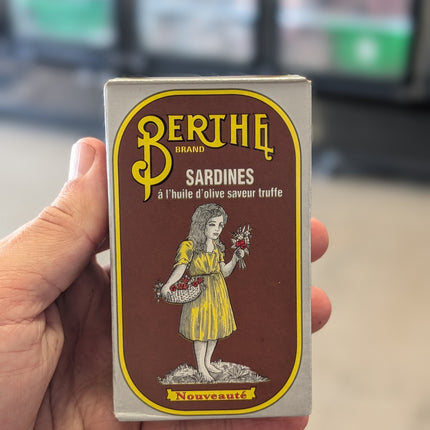 Hand holding a vintage Bertha brand sardines packaging box.