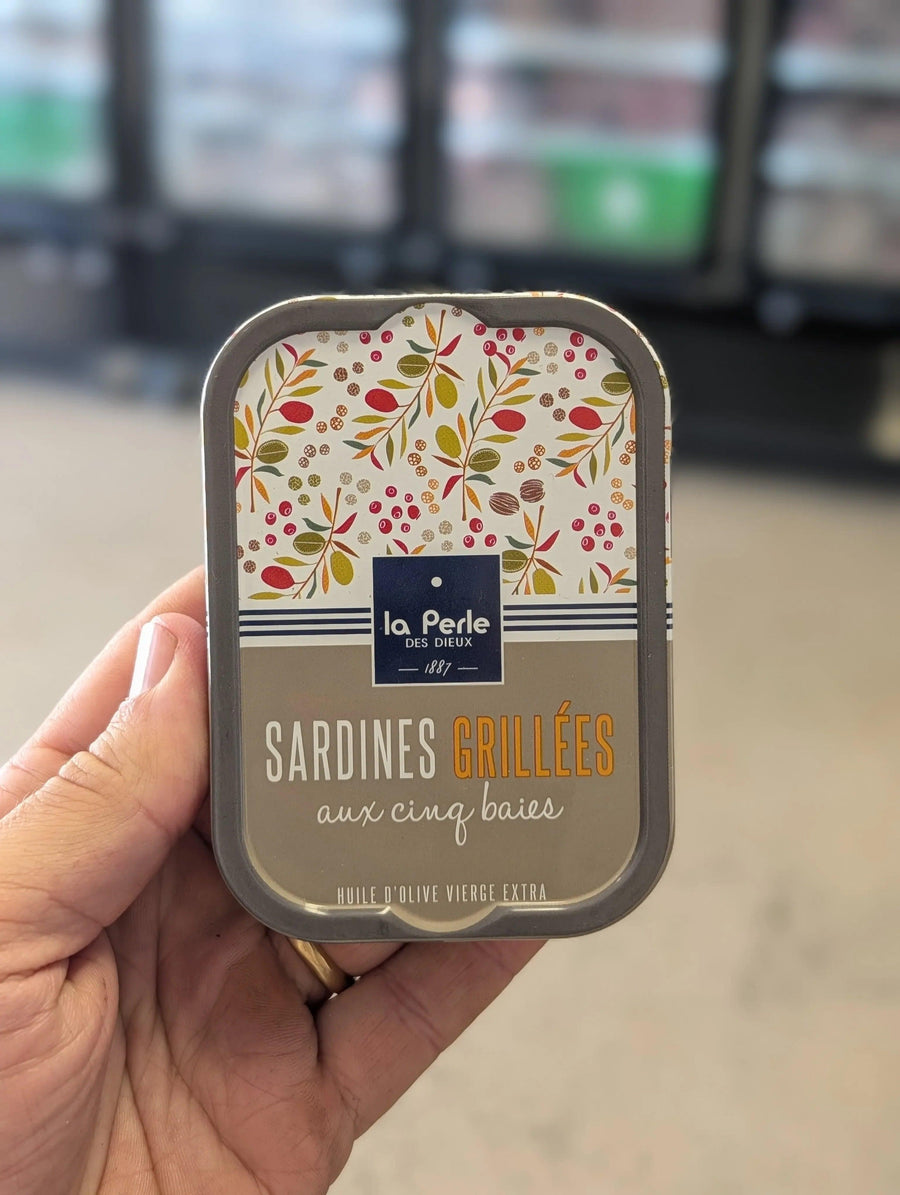 Hand holding a can of 'Sardines Grillées' with floral design on the label. — view 2