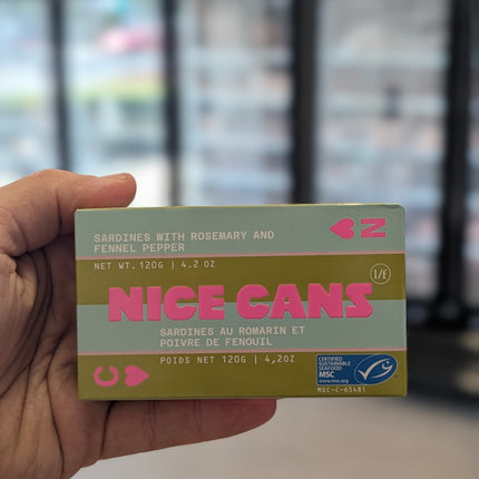 Hand holding a box of 'Nice Cans' with a blurred background