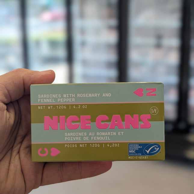 Hand holding a box of 'Nice Cans' with a blurred background