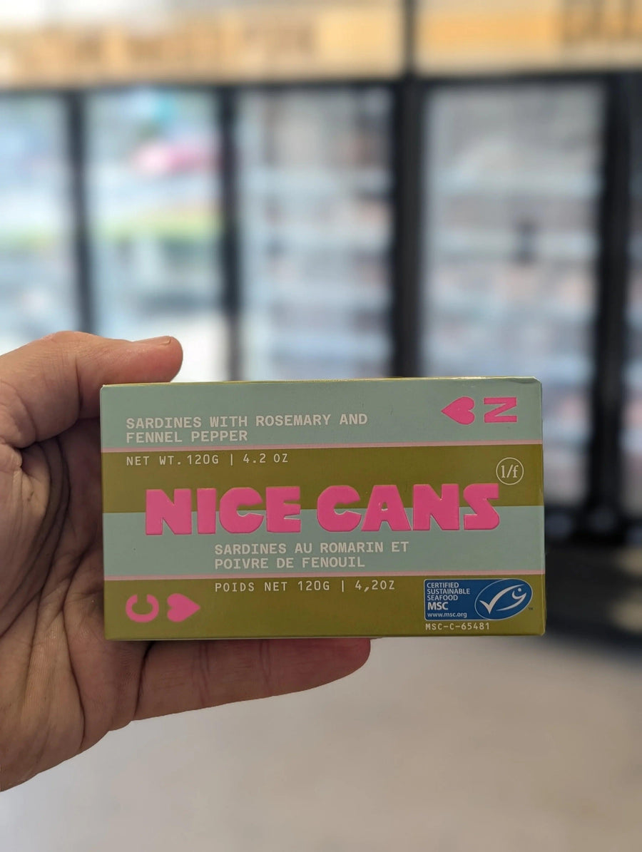Hand holding a box of 'Nice Cans' with a blurred background — view 2