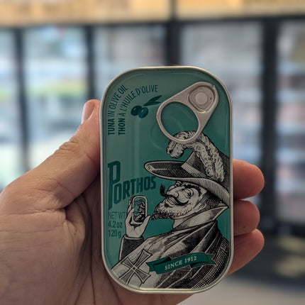 Hand holding a can with a decorative label featuring a graphic design.