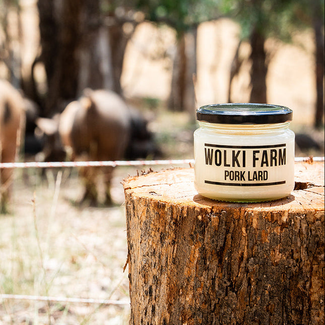 Wolki Farm pork lard container on a tree stump with pigs in the background