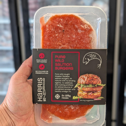 Packaged salmon burgers held in a hand with a blurred background