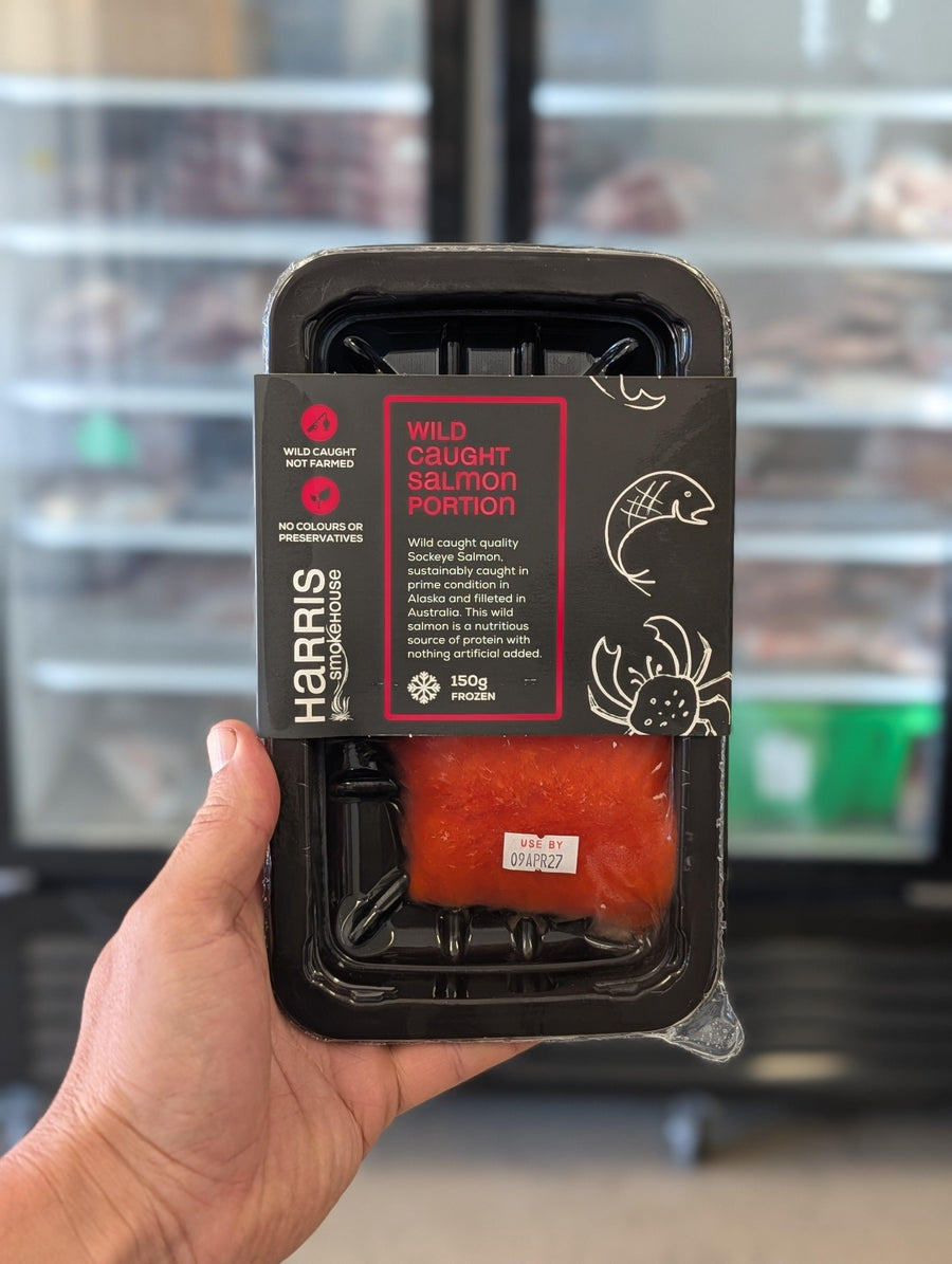 Hand holding a package of wild-caught salmon with 'Harris' branding. — view 2
