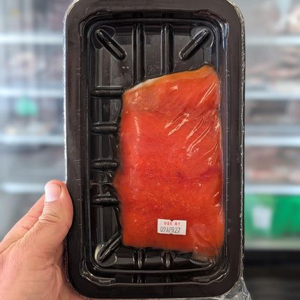 Hand holding a package of raw salmon with a blurred background