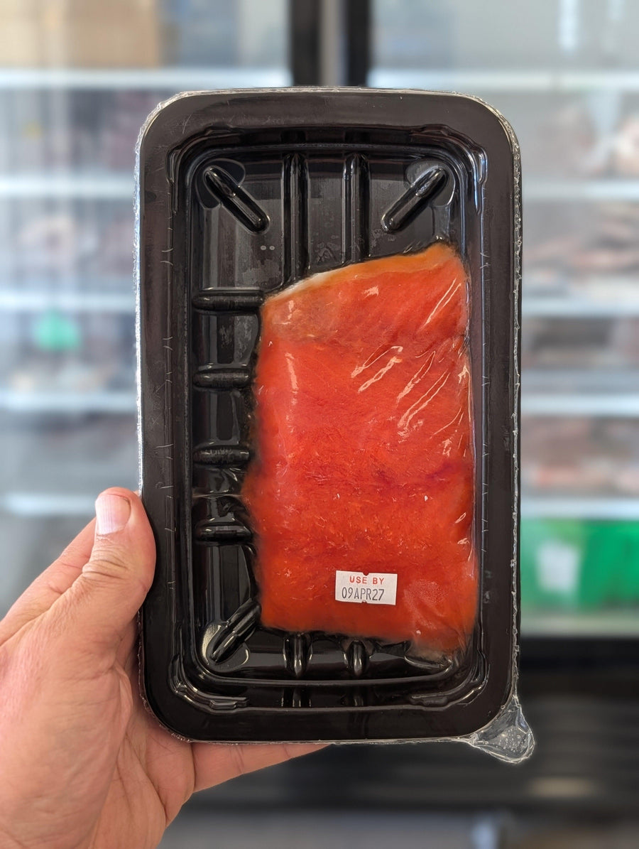Hand holding a package of raw salmon with a blurred background — view 3