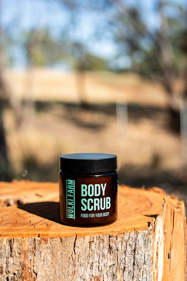 Jar of body scrub on a wooden log with a blurred natural background
