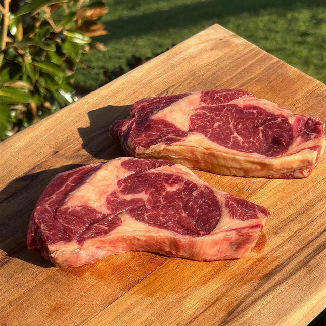 Thick-cut marbled Wolki Farm double aged dairy beef steaks on a timber board in golden farm light