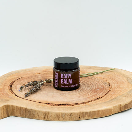 Jar of baby balm on a wooden board with lavender, against a white background