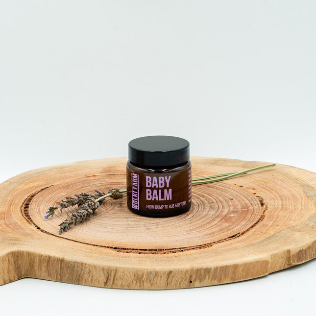 Jar of baby balm on a wooden board with lavender, against a white background