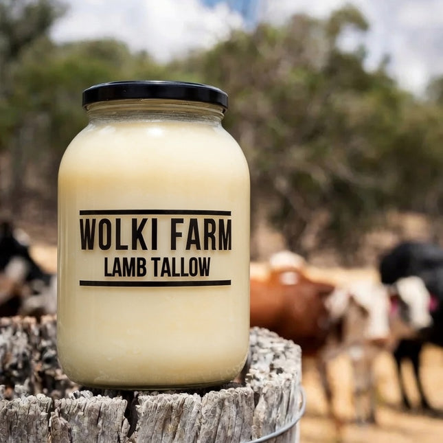 Jar of Wolki Farm Lamb Tallow on a wooden post with cows in the background