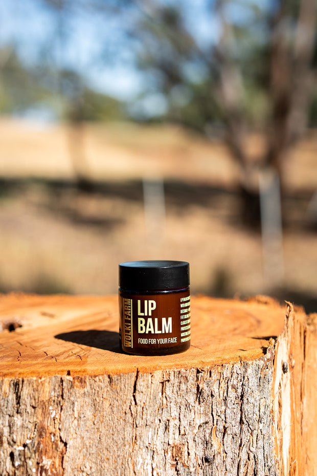 Lip balm jar on a wooden log with a blurred natural background